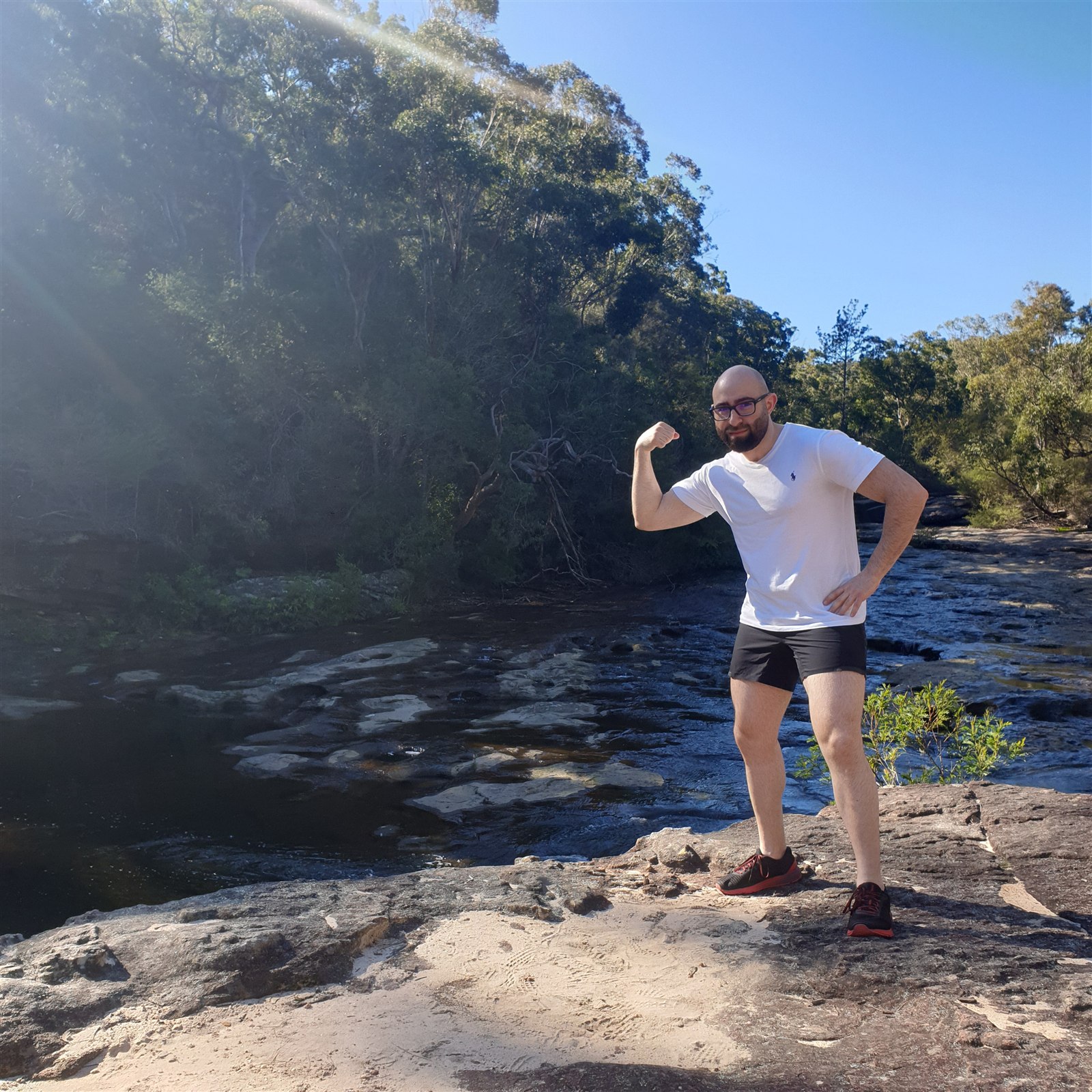 Joseph Bitar posing on rocks beside a river